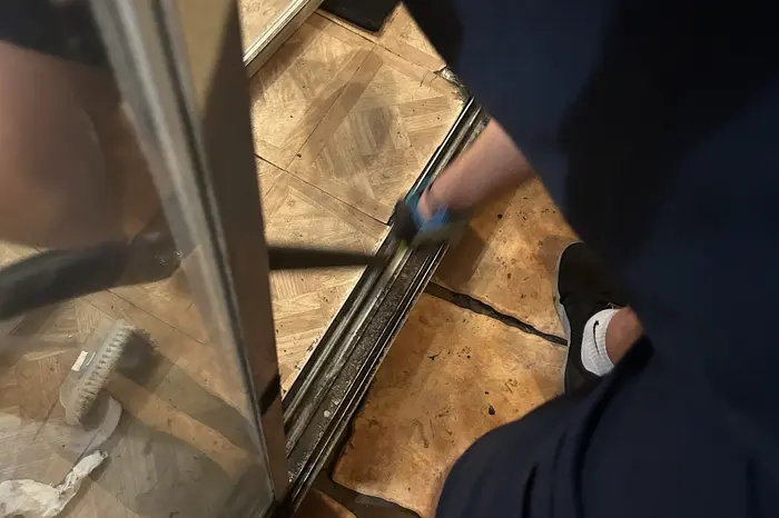 Sliding door bottom track being serviced during a roller replacement