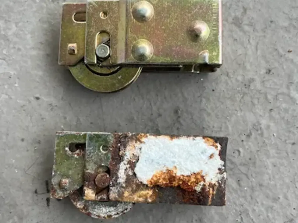 A new heavy-duty sliding door roller beside a corroded, seized original roller