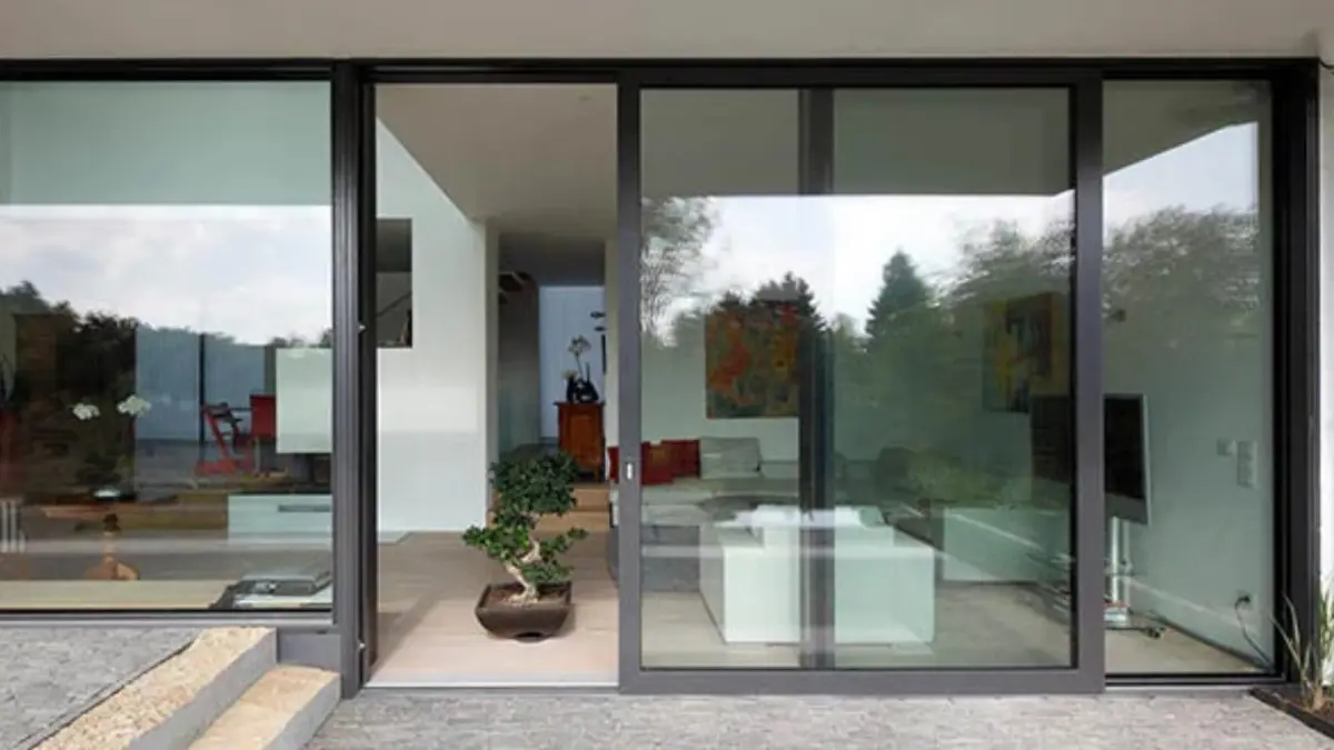 A coastal home's black-framed sliding doors exposed to salt air
