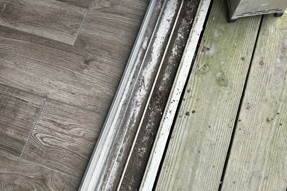 Corroded, debris-packed sliding door bottom track before repair