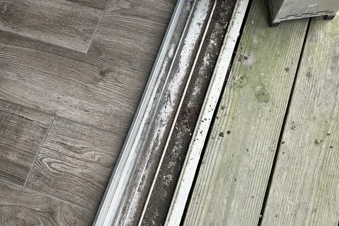 Sliding door track packed with sand, grime and corrosion