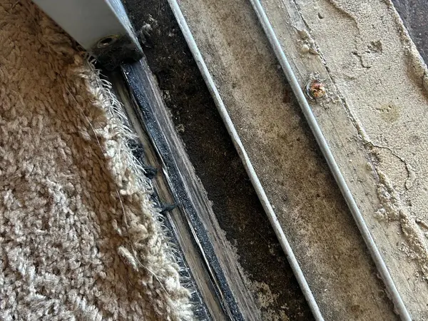 Corroded and debris-packed sliding door bottom track before repair