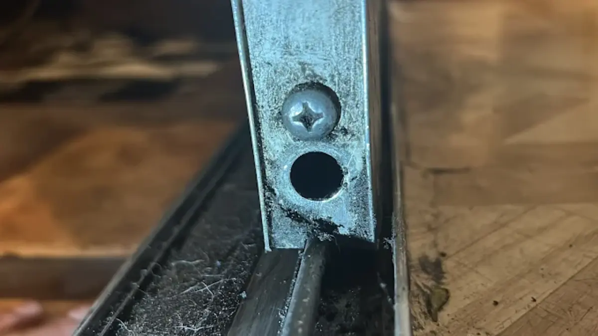 Sliding door bottom rail showing a roller adjustment screw